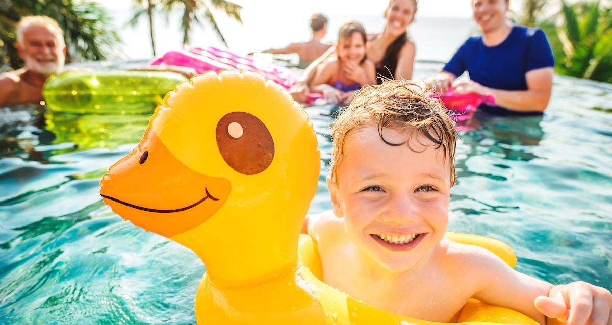 Boy swimming in a pool with family