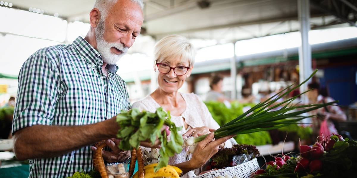 Mature couple shopping vegetables and fruits on the market. Healthy diet.
