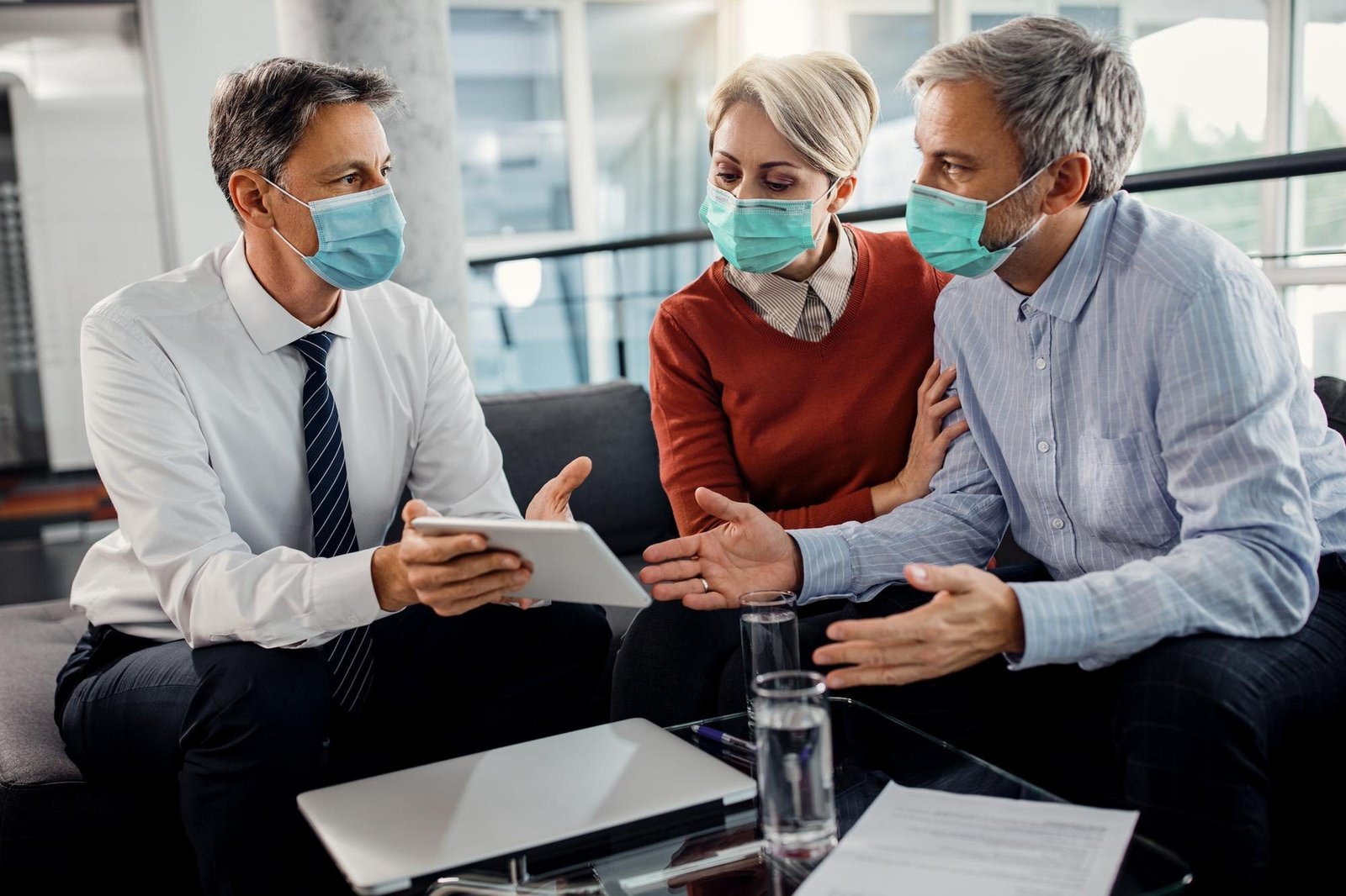 insurance-agent-couple-wearing-face-masks-while-using-touchpad-office_637285-11104