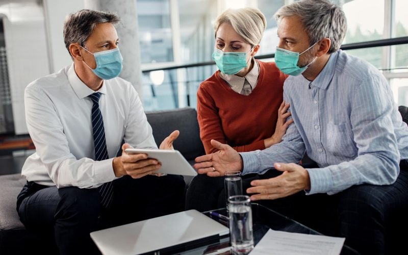 insurance-agent-couple-wearing-face-masks-while-using-touchpad-office_637285-11104